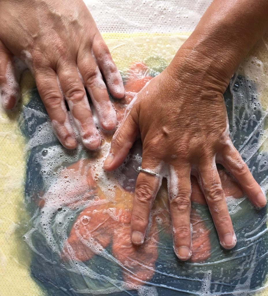 Close up shot of hands making art, full of blues and reds and bubbles
